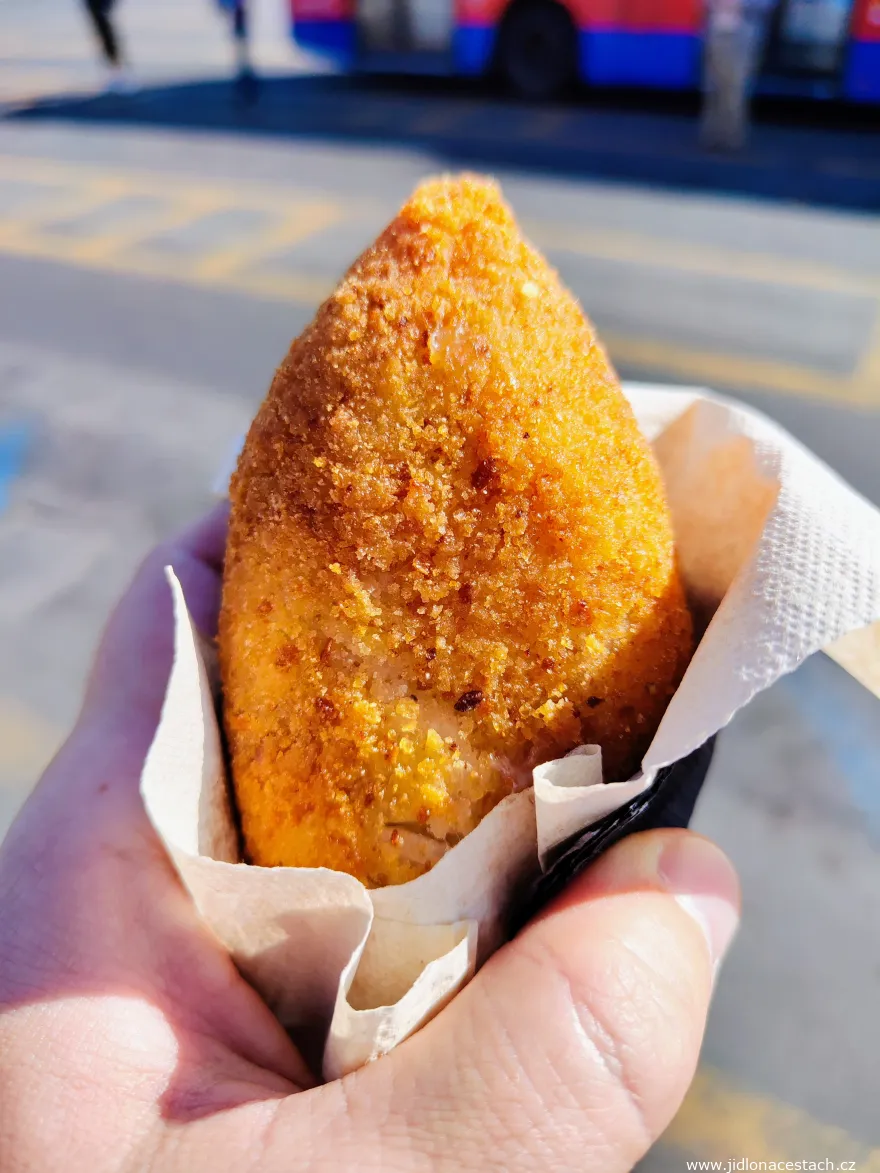 A pointed arancino from Catania in a paper napkin.