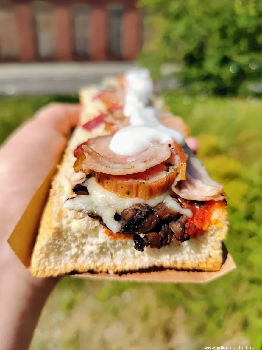 Zapiekanka mit Champignons, Tomaten, Käse, Wurst, Speck, Gewürzgurke und Knoblauchsoße.