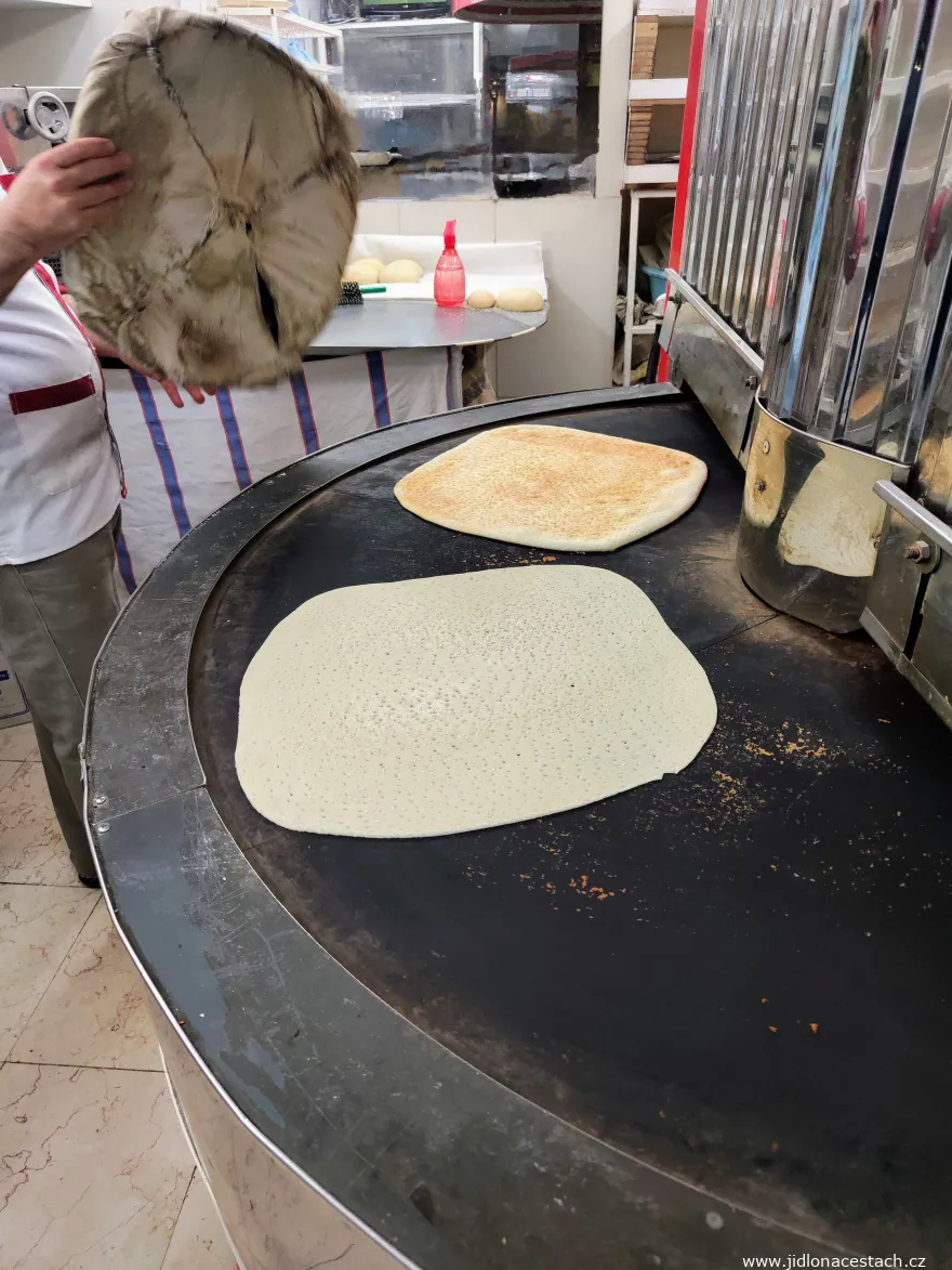Le boulanger dépose un nouveau nan-e ghandi sur le four rotatif. Le boulanger dépose un nouveau nan-e ghandi sur le four rotatif.