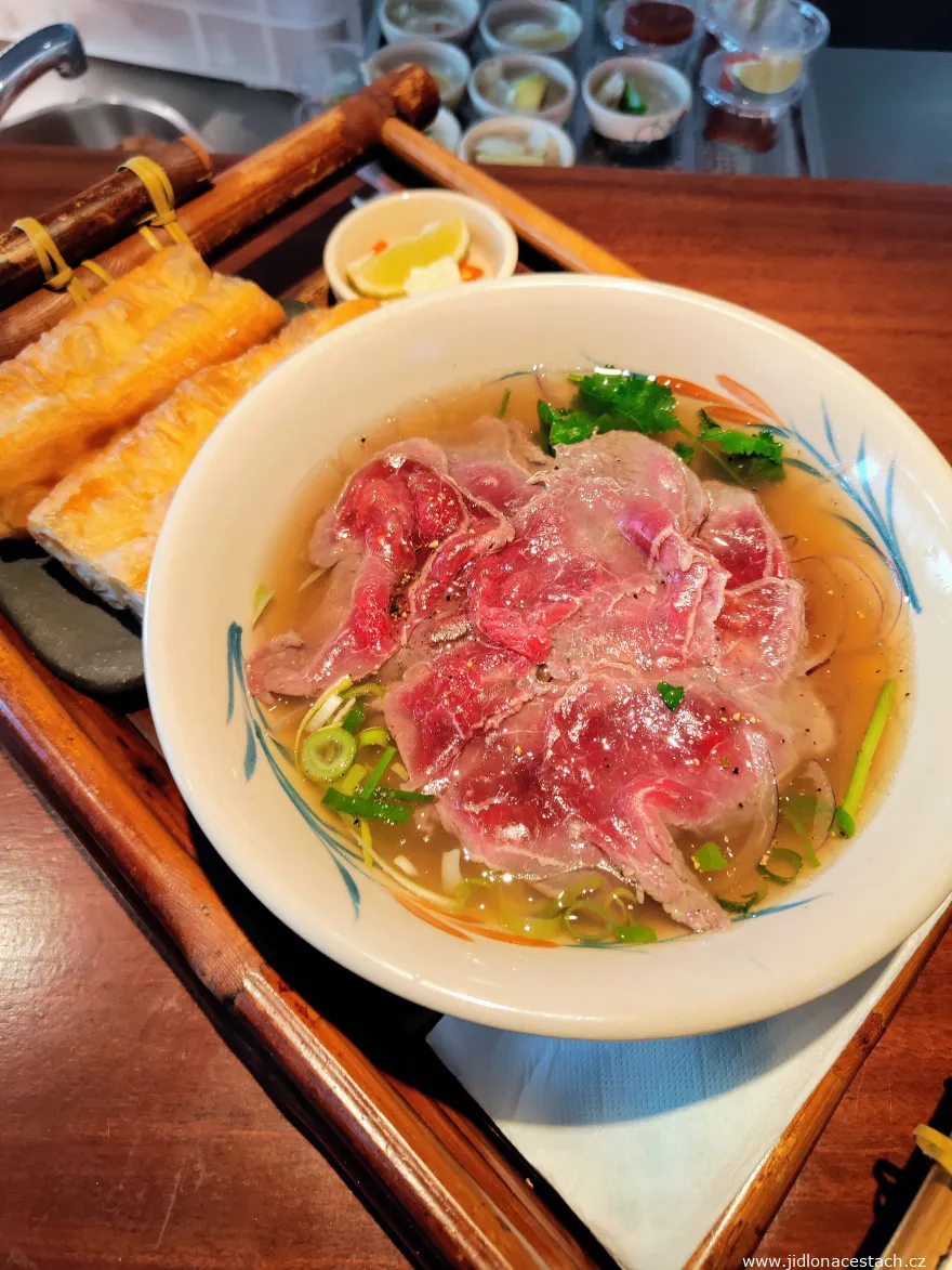 Phở bò tái: hovädzí vývar, domáce ryžové rezance, hovädzie tataki z roštenky (medium), nakladaný cesnak, sriracha (295 Kč/11,80 EUR) a chrumkavé tyčinky quẩy (+ 45 Kč/1,80 EUR). Phở bò tái: hovädzí vývar, domáce ryžové rezance, hovädzie tataki z roštenky (medium), nakladaný cesnak, sriracha (295 Kč/11,80 EUR) a chrumkavé tyčinky quẩy (+ 45 Kč/1,80 EUR).