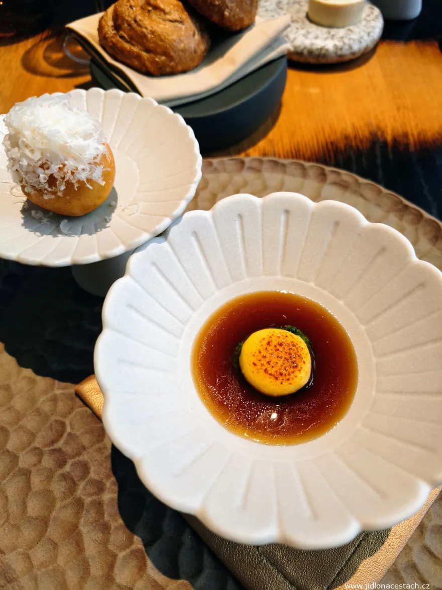 Restaurace Field, amuse bouche: pralinka ze zrajícího sýru s libečkovým pestem, consommé z kváskového chleba a langoš s bylinkovou emulzí, gelovým žloutkem a stařeným sýrem Gran Moravia.