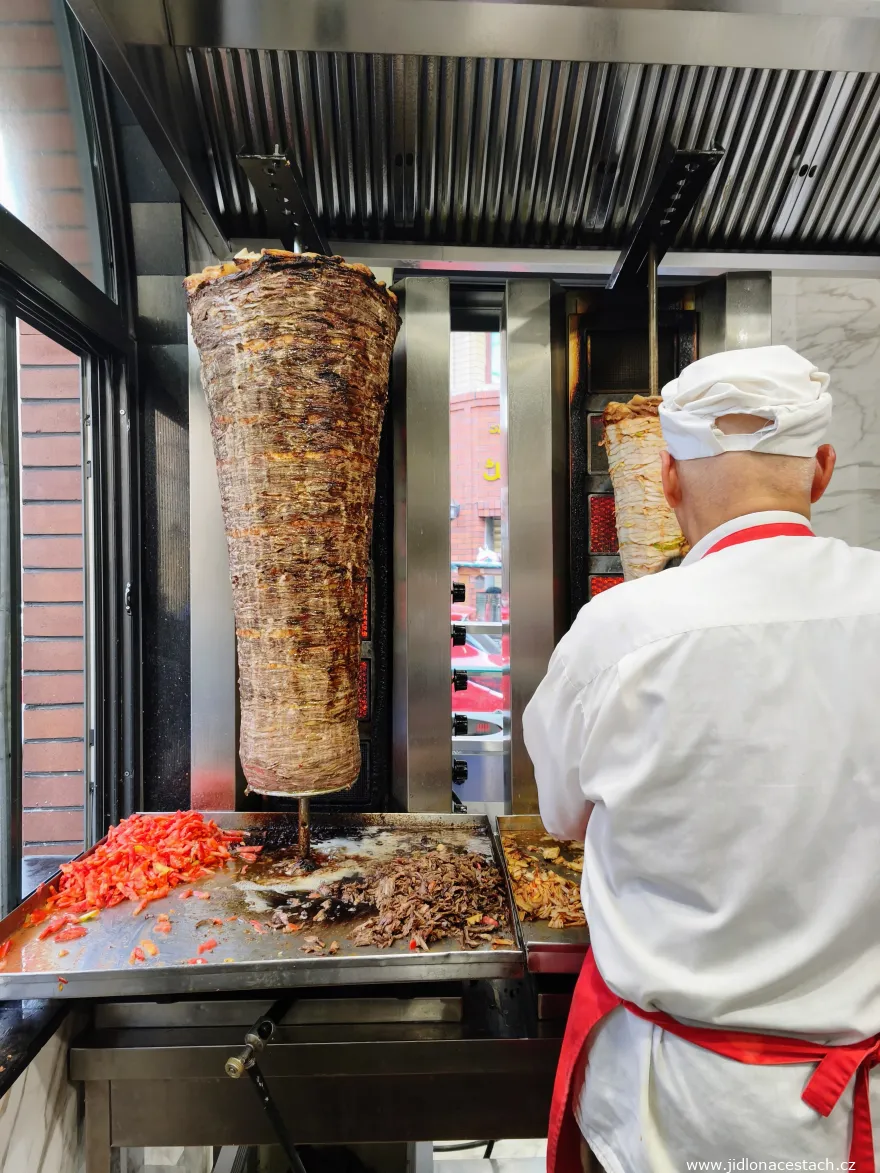 Döner kebab: vľavo hovädzí variant, vpravo, čiastočne schovaný kuchárom, kurací variant.