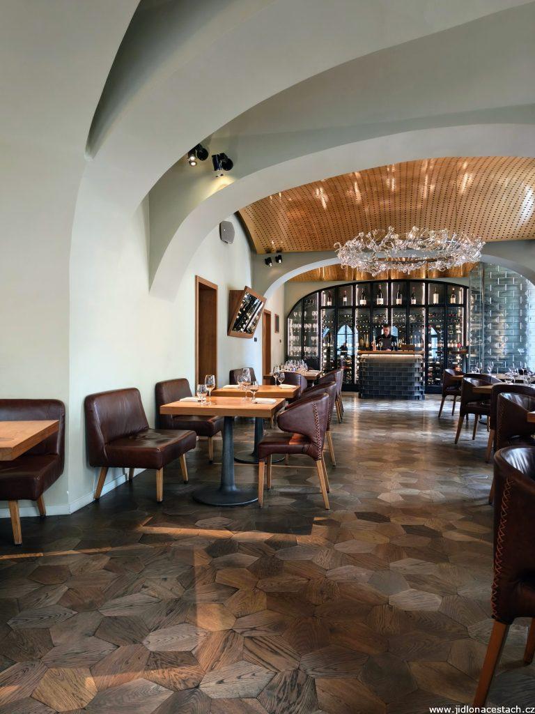 Restaurace La Degustation Bohême Bourgeoise: jednoduchý interiér s dominantním lustrem.